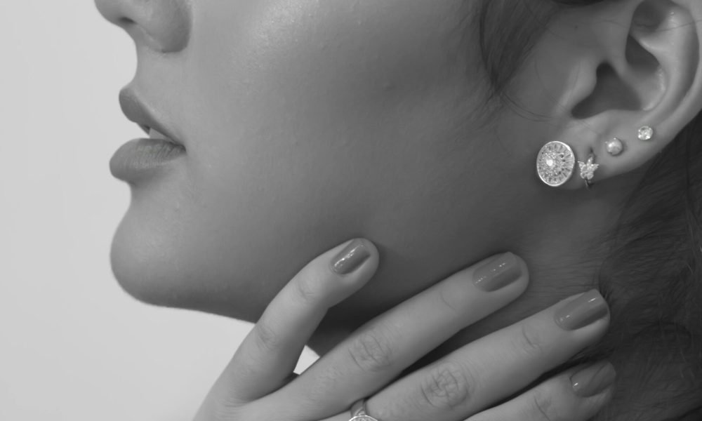 A black and white portrait of a woman with jewelry, eyes closed, in a serene pose.