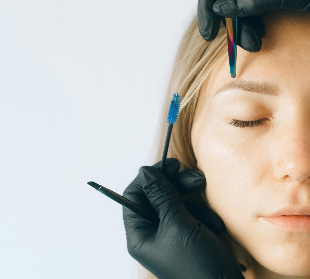 Close-up of a woman receiving professional eyebrow and lash treatment in a beauty salon.